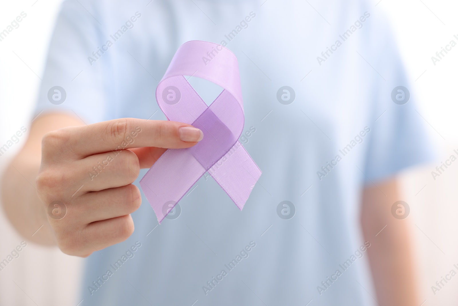 Photo of Woman with violet ribbon on light background, closeup. Alzheimer disease, epilepsy and pancreas cancer awareness