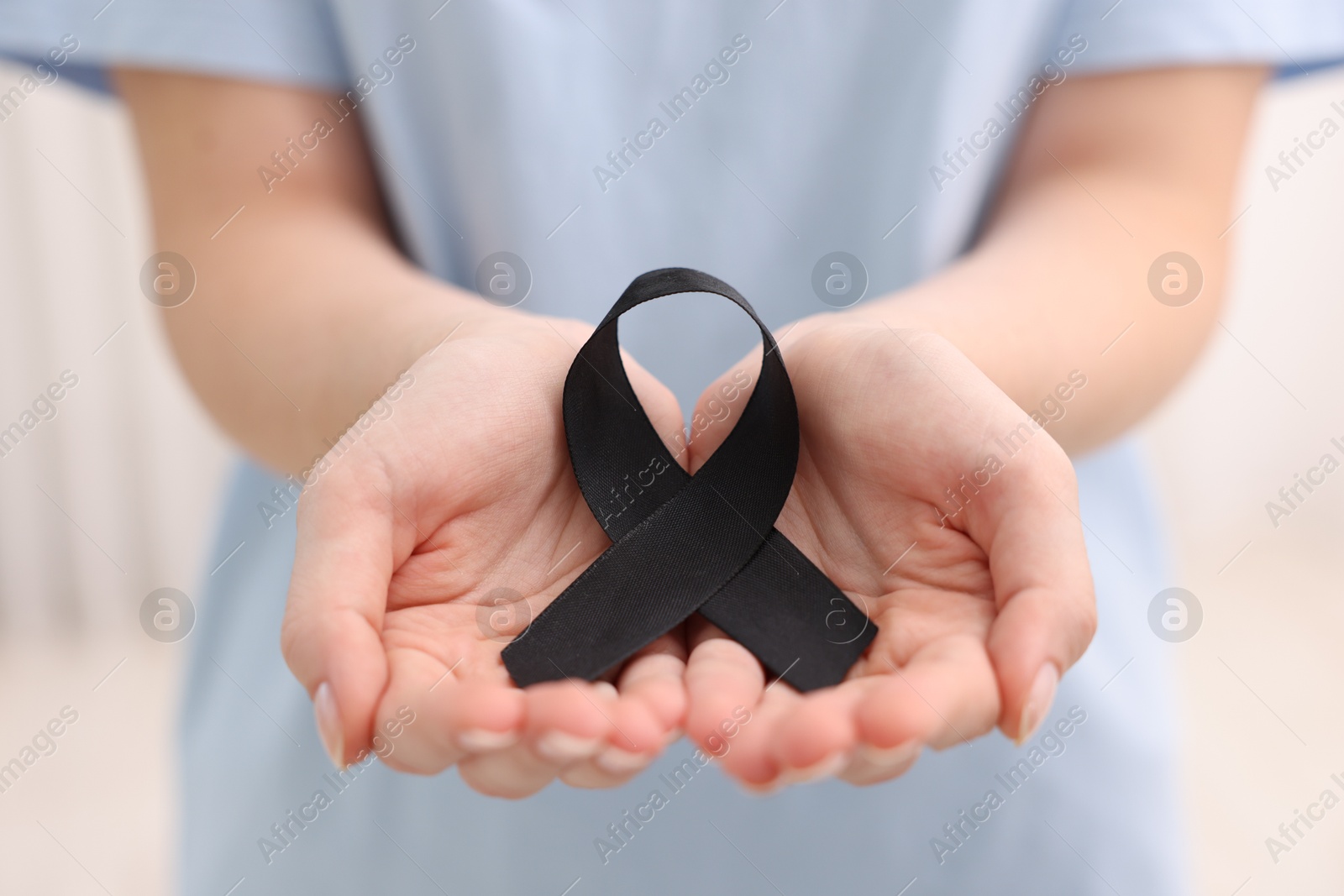 Photo of Woman with black ribbon on light background, closeup. Melanoma and mourning concept