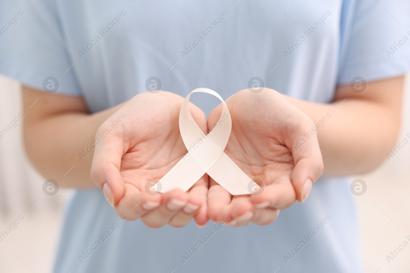 Photo of Woman with white ribbon on light background, closeup. Bone cancer and lung disease awareness