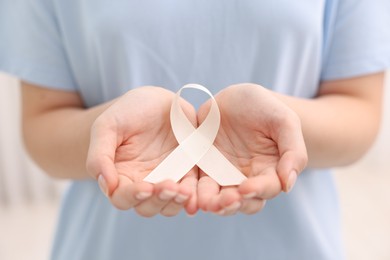 Photo of Woman with white ribbon on light background, closeup. Bone cancer and lung disease awareness