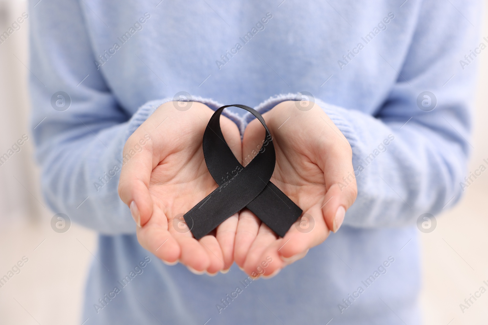 Photo of Woman with black ribbon on light background, closeup. Melanoma and mourning concept