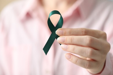 Photo of Woman with teal ribbon, closeup. Ovarian cancer and gynecological disorders awareness