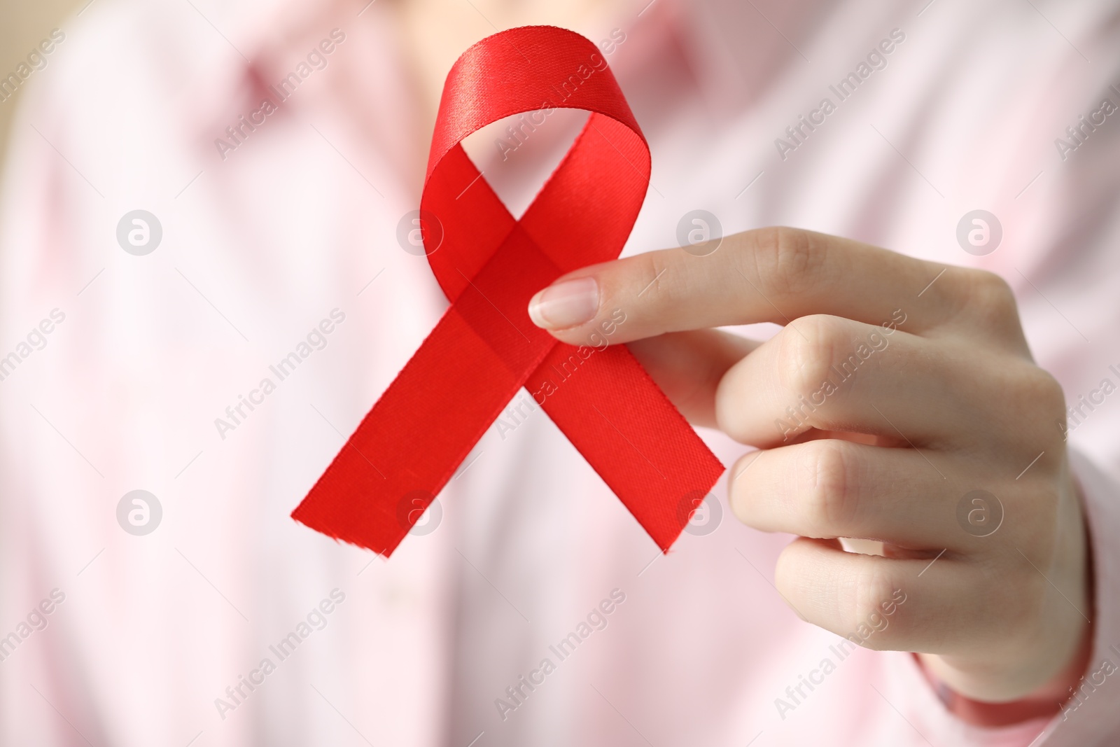 Photo of Woman with red ribbon, closeup. HIV (AIDS) disease awareness