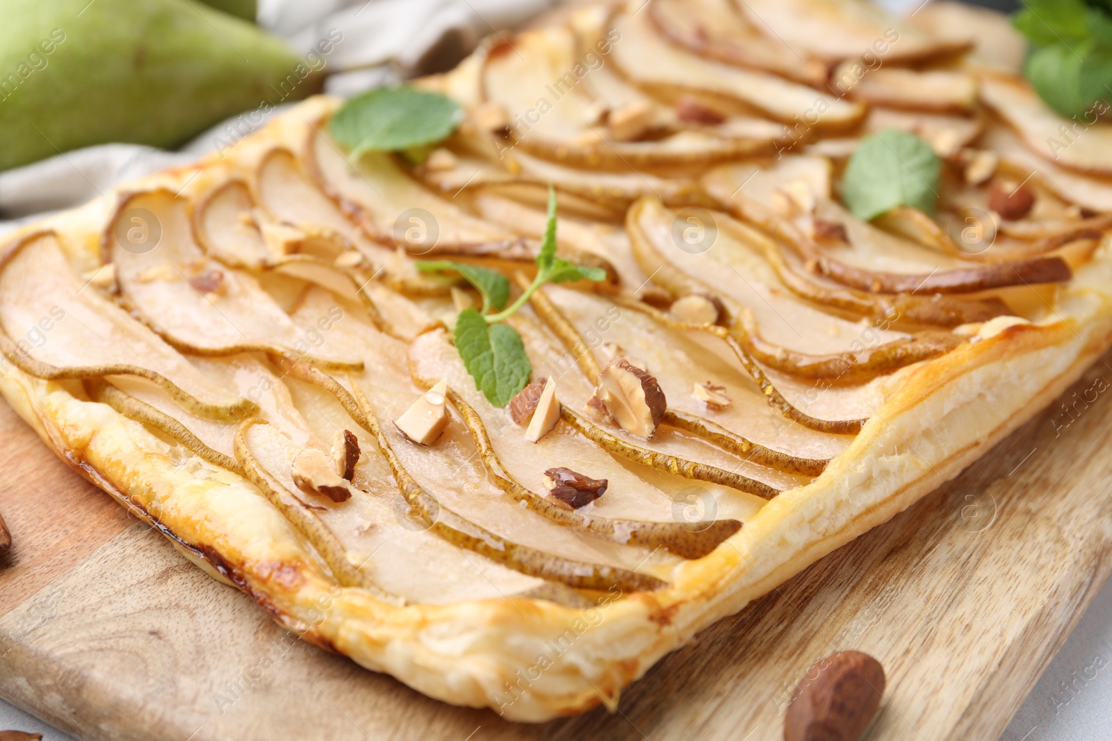 Photo of Delicious puff pastry tart with pears, almond and mint on table, closeup