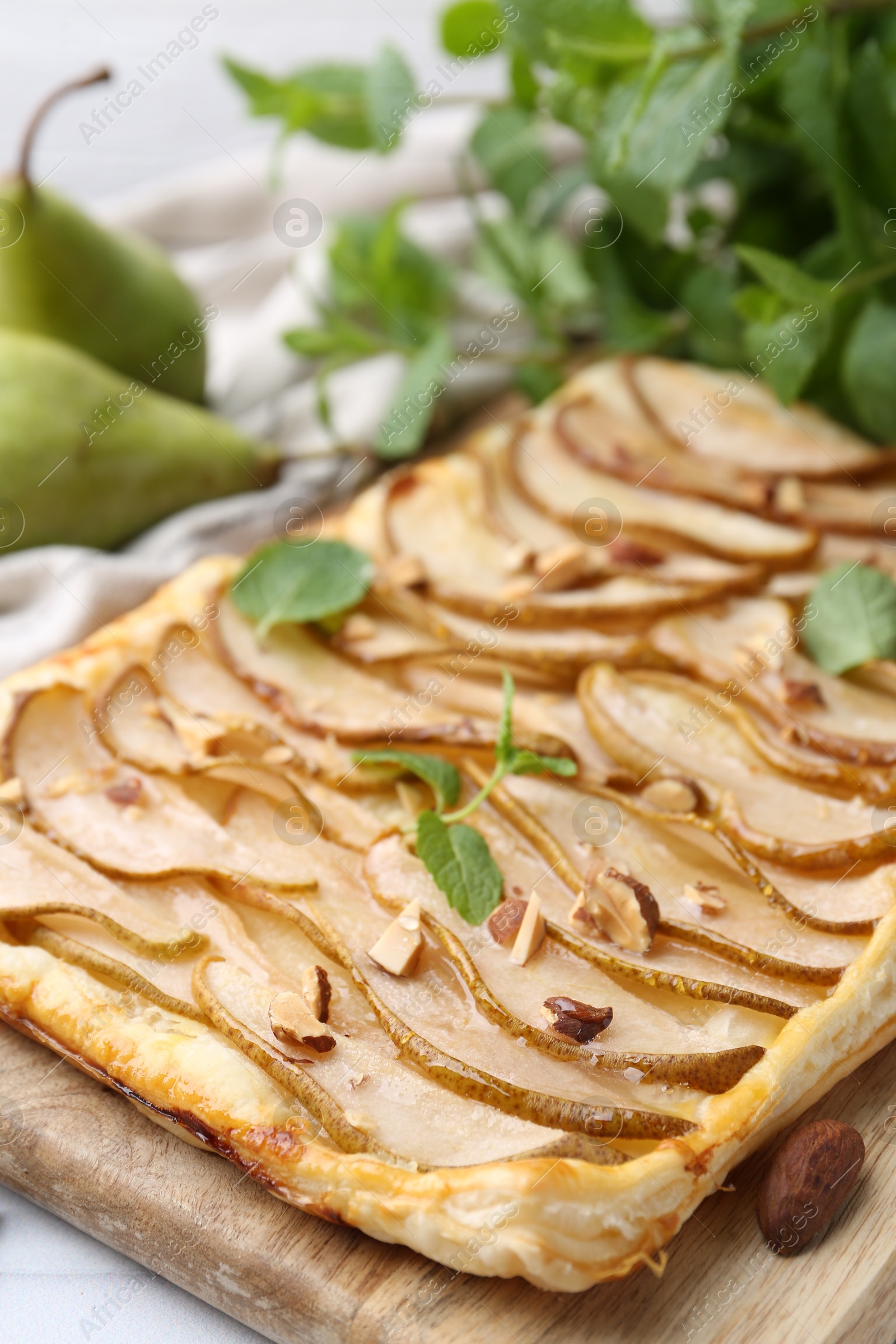 Photo of Delicious puff pastry tart with pears, almond and mint on table, closeup