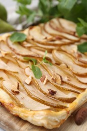 Photo of Delicious puff pastry tart with pears, almond and mint on board, closeup