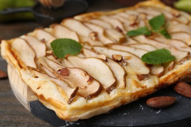 Delicious puff pastry tart with pears, almond and mint on wooden table, closeup