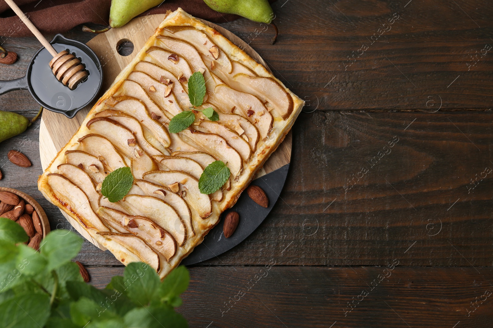 Photo of Delicious puff pastry tart with pears, almond and mint on wooden table, flat lay. Space for text