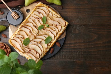 Delicious puff pastry tart with pears, almond and mint on wooden table, flat lay. Space for text