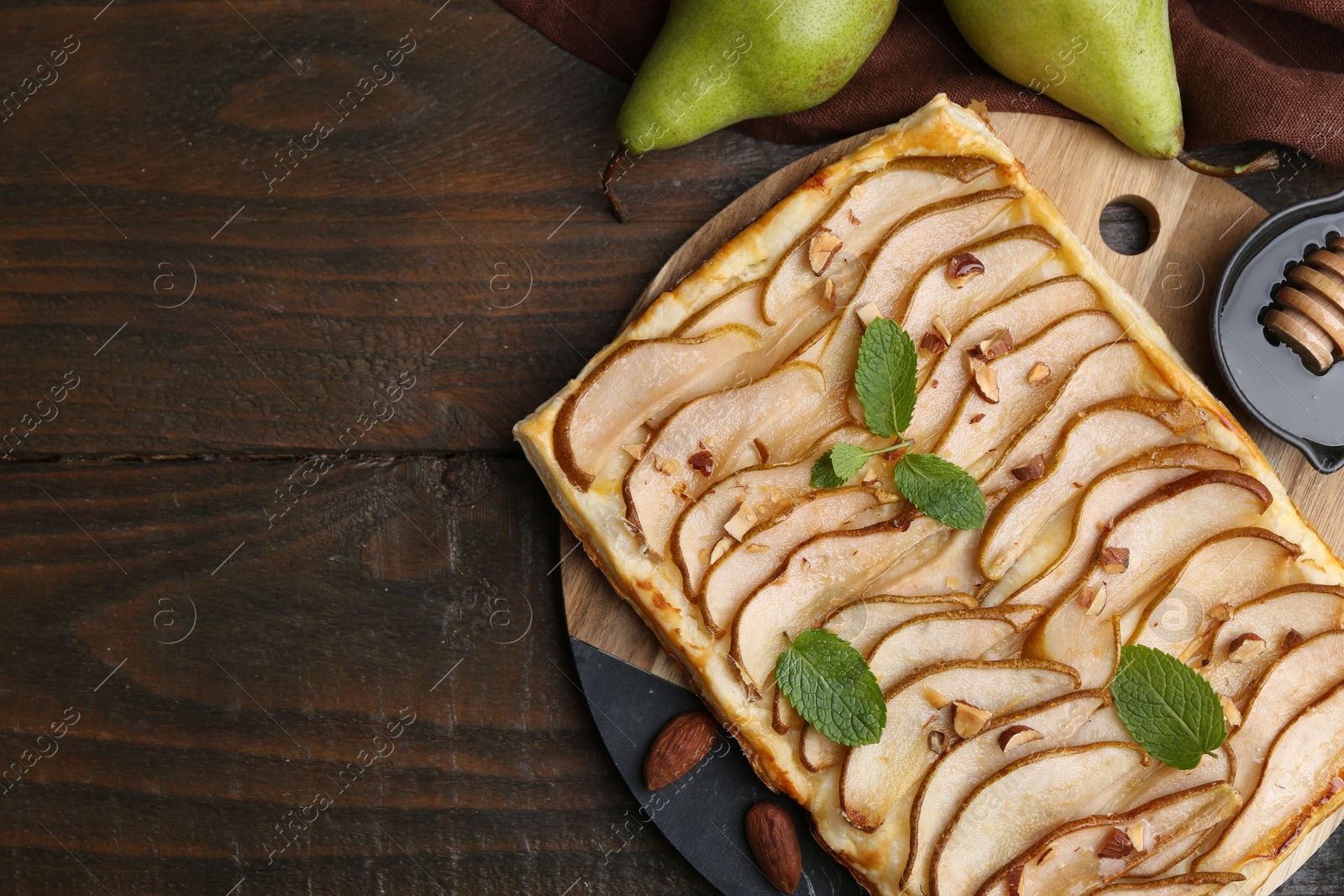 Photo of Delicious puff pastry tart with pears, almond and mint on wooden table, flat lay. Space for text