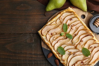 Delicious puff pastry tart with pears, almond and mint on wooden table, flat lay. Space for text