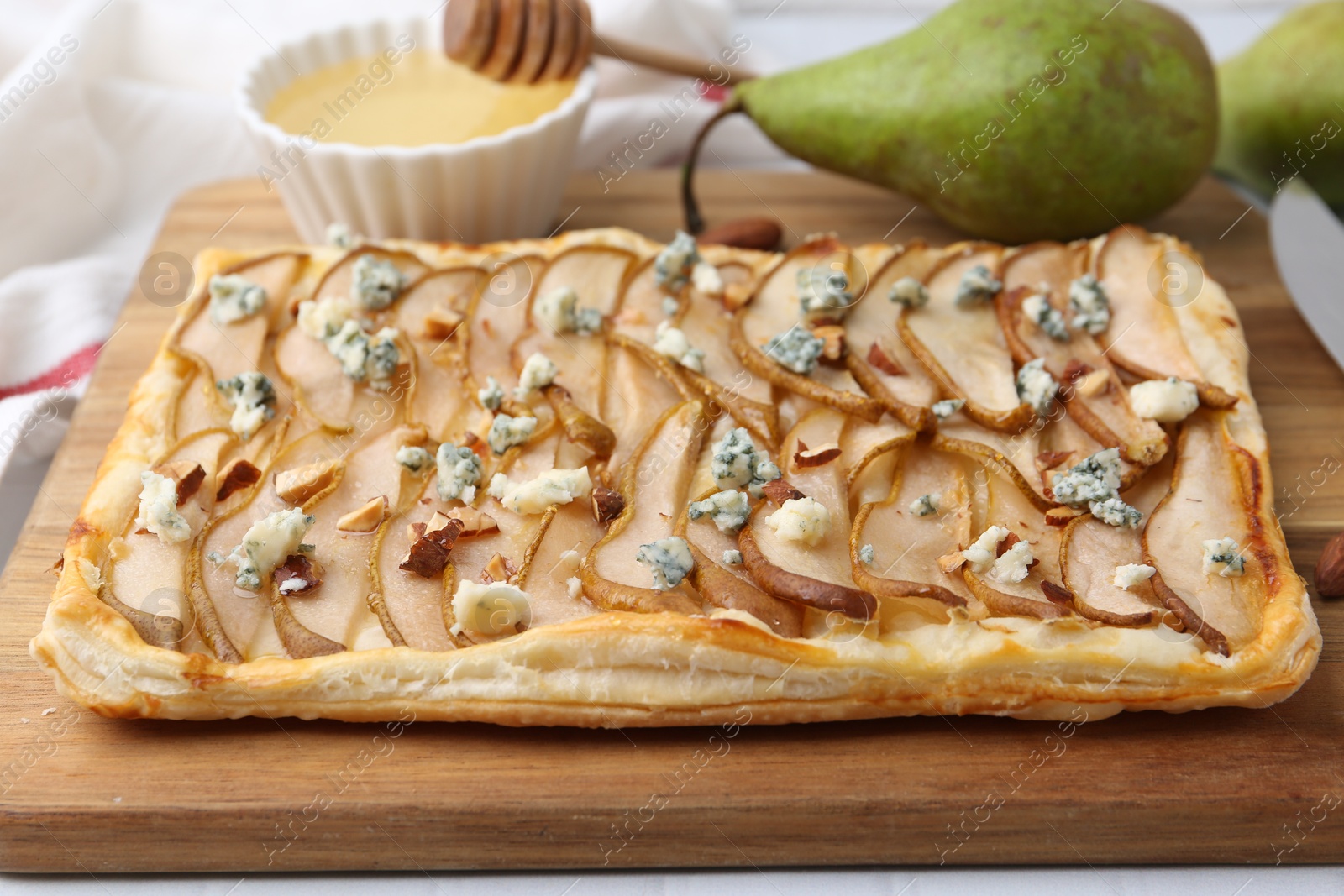 Photo of Delicious puff pastry tart with pears, almond and blue cheese on light table, closeup