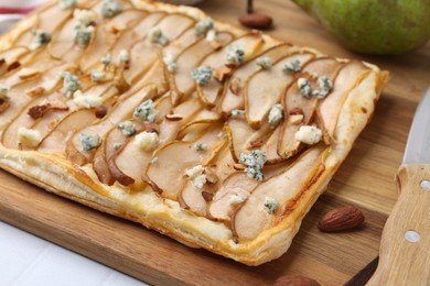 Photo of Delicious puff pastry tart with pears, almond and blue cheese on light table, closeup