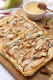 Photo of Delicious puff pastry tart with pears, almond and blue cheese on light table, closeup