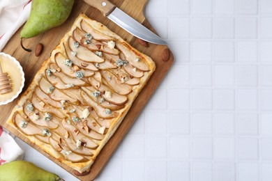 Photo of Delicious puff pastry tart with pears, almond, honey and blue cheese on light tiled table, flat lay. Space for text