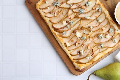 Photo of Delicious puff pastry tart with pears, almond, honey and blue cheese on light tiled table, flat lay. Space for text