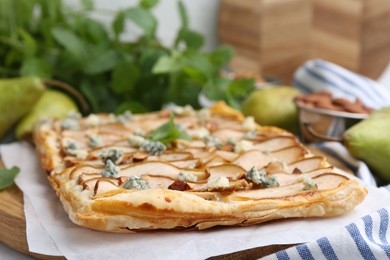 Photo of Delicious puff pastry tart with pears, almond, mint and blue cheese on table, closeup