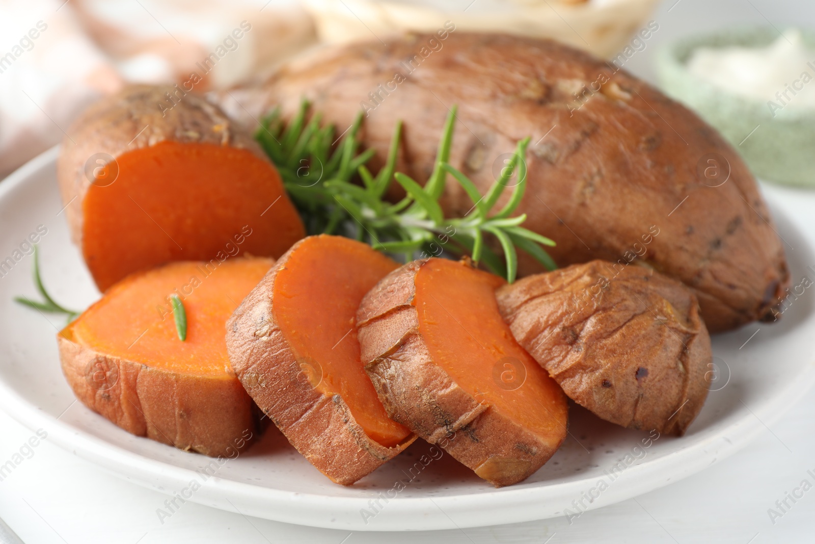 Photo of Tasty cooked sweet potatoes and rosemary on table, closeup