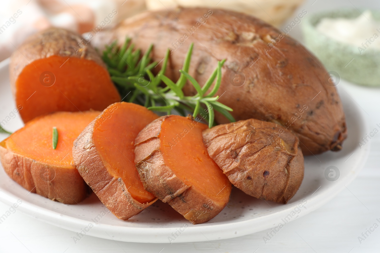 Photo of Tasty cooked sweet potatoes and rosemary on table, closeup