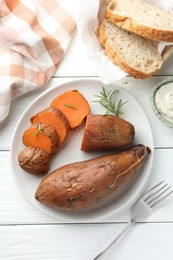 Photo of Tasty cooked sweet potatoes served with rosemary and sauce on white wooden table, top view