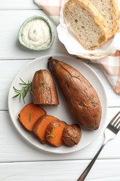 Photo of Tasty cooked sweet potatoes served with rosemary and sauce on white wooden table, top view