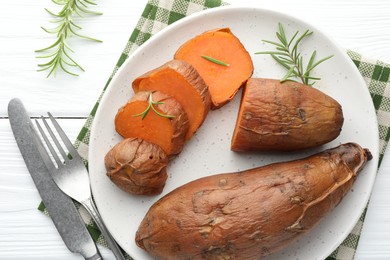 Photo of Tasty cooked sweet potatoes served with rosemary on white wooden table, top view