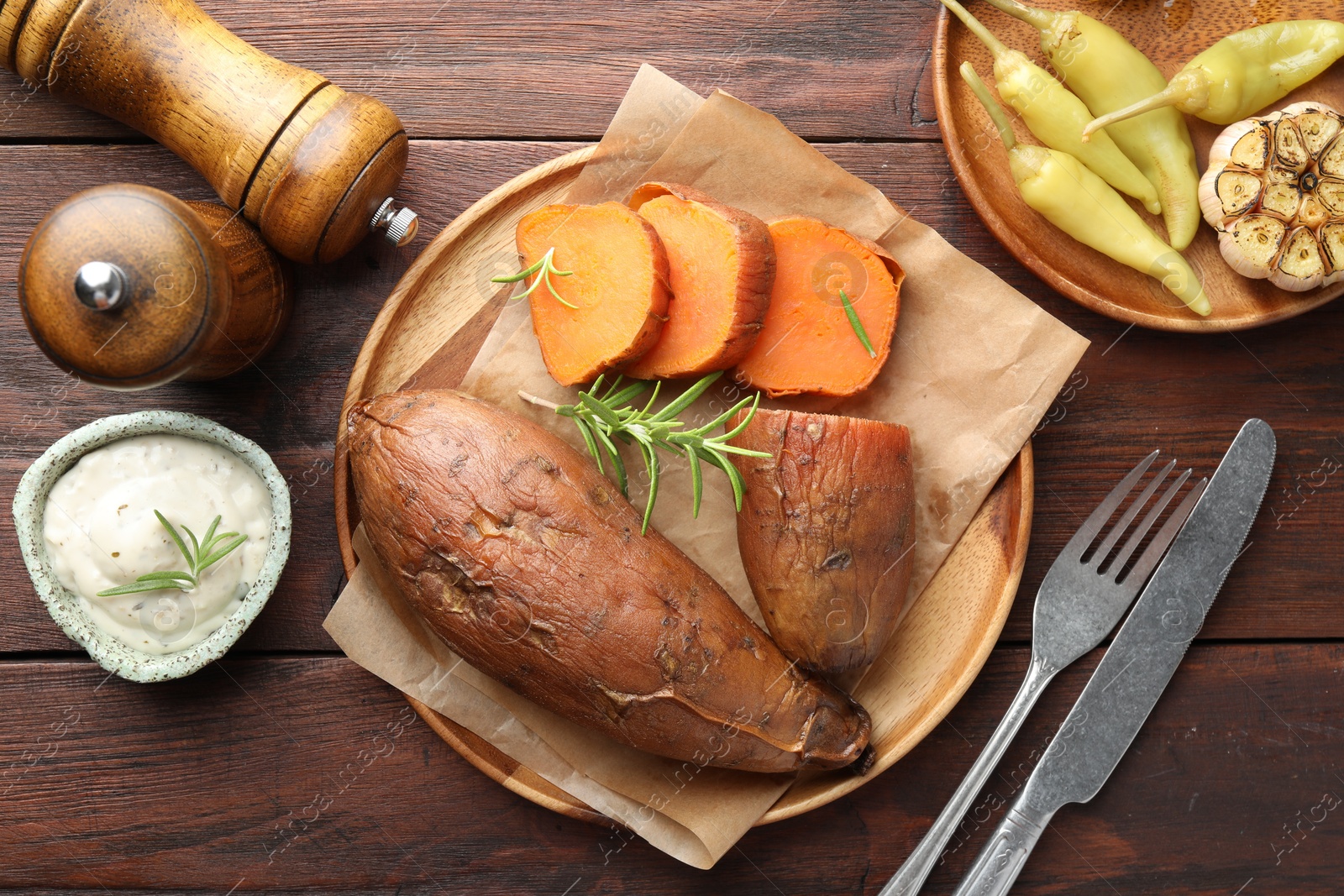 Photo of Tasty cooked sweet potatoes served with rosemary and sauce on wooden table, top view