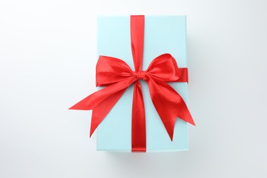 Photo of Beautiful gift box with red bow isolated on white, top view