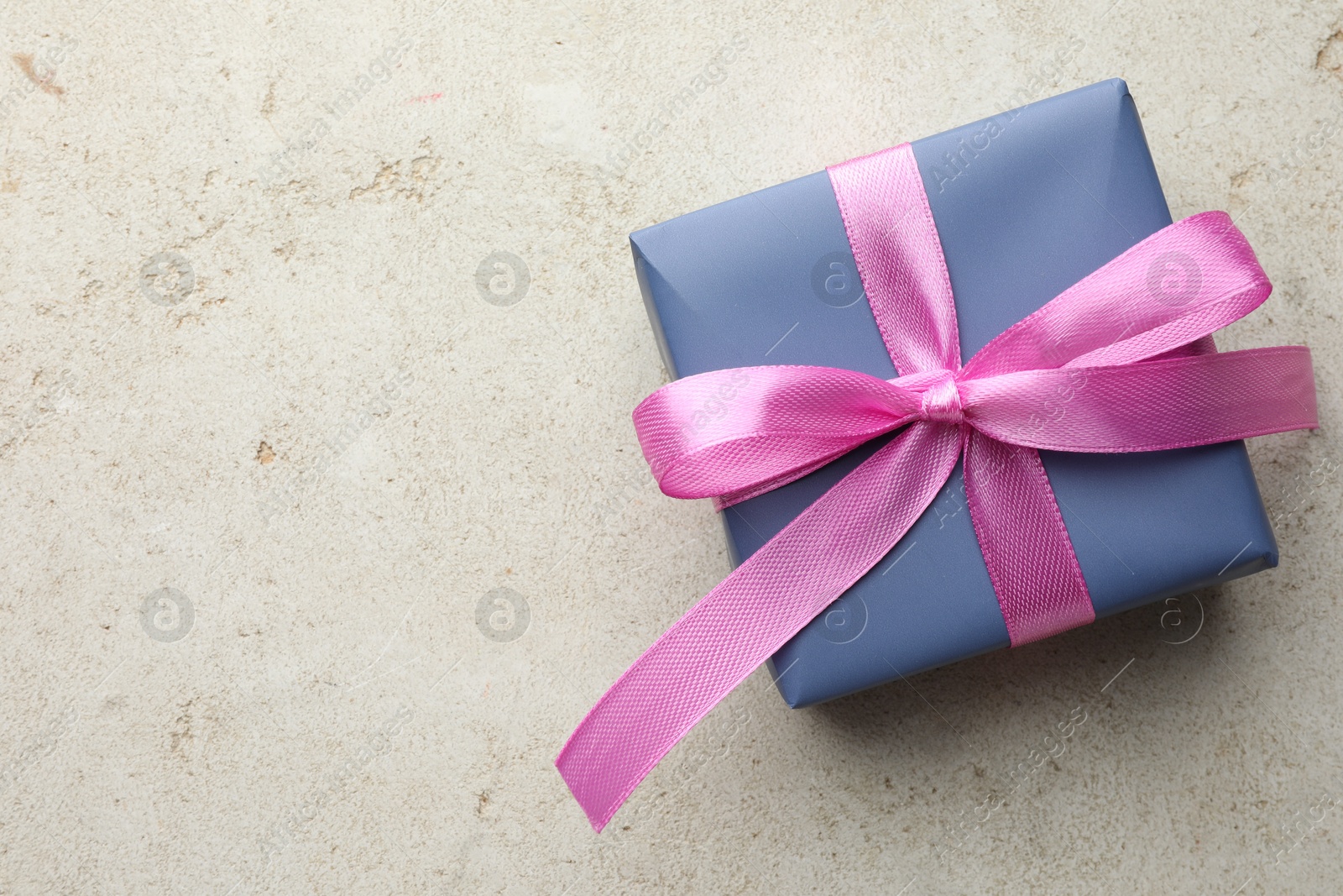 Photo of Beautiful gift box with pink bow on light grey table, top view. Space for text