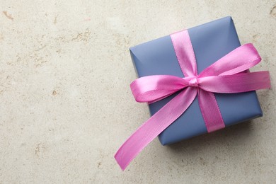 Photo of Beautiful gift box with pink bow on light grey table, top view. Space for text