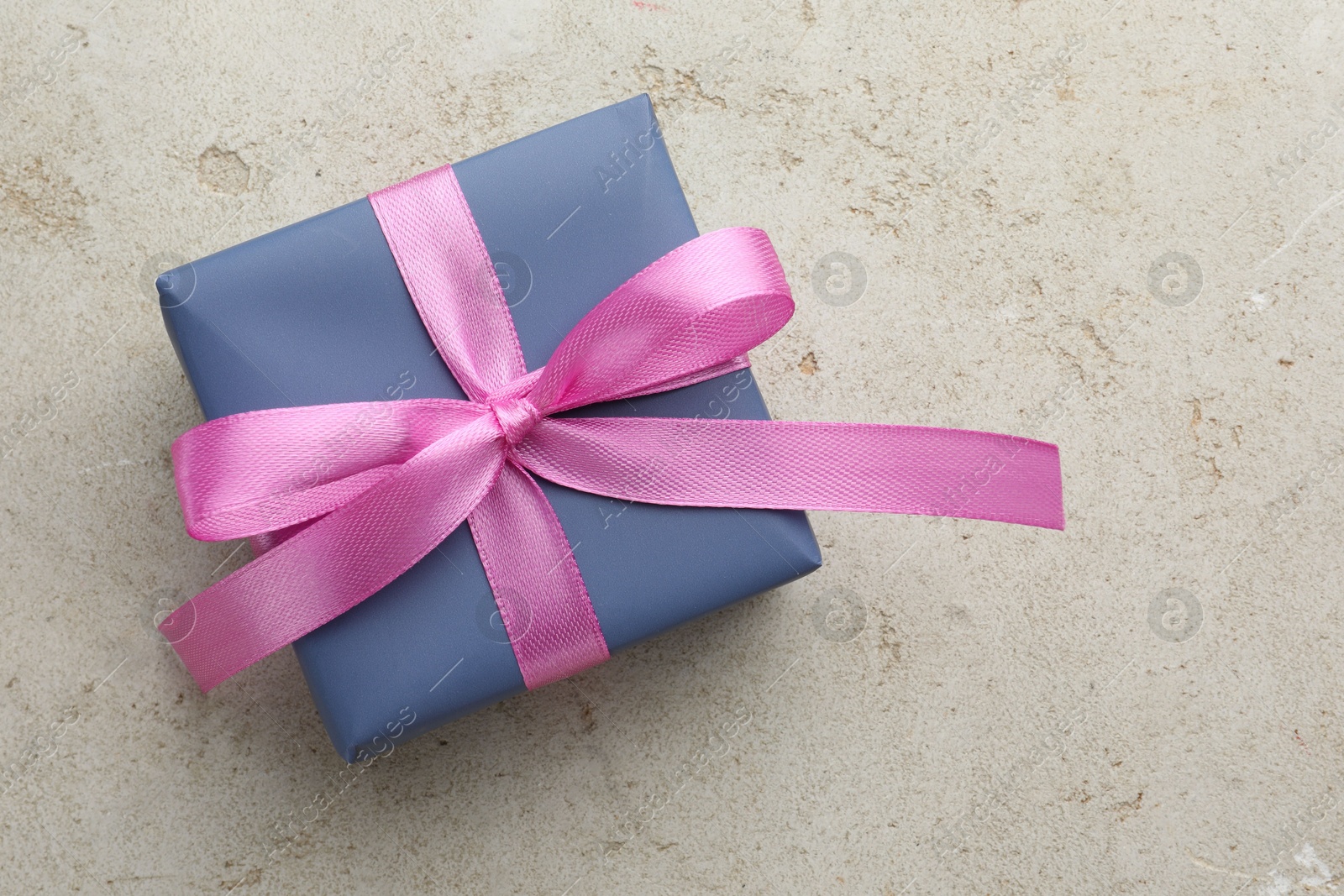 Photo of Beautiful gift box with pink bow on light grey table, top view. Space for text