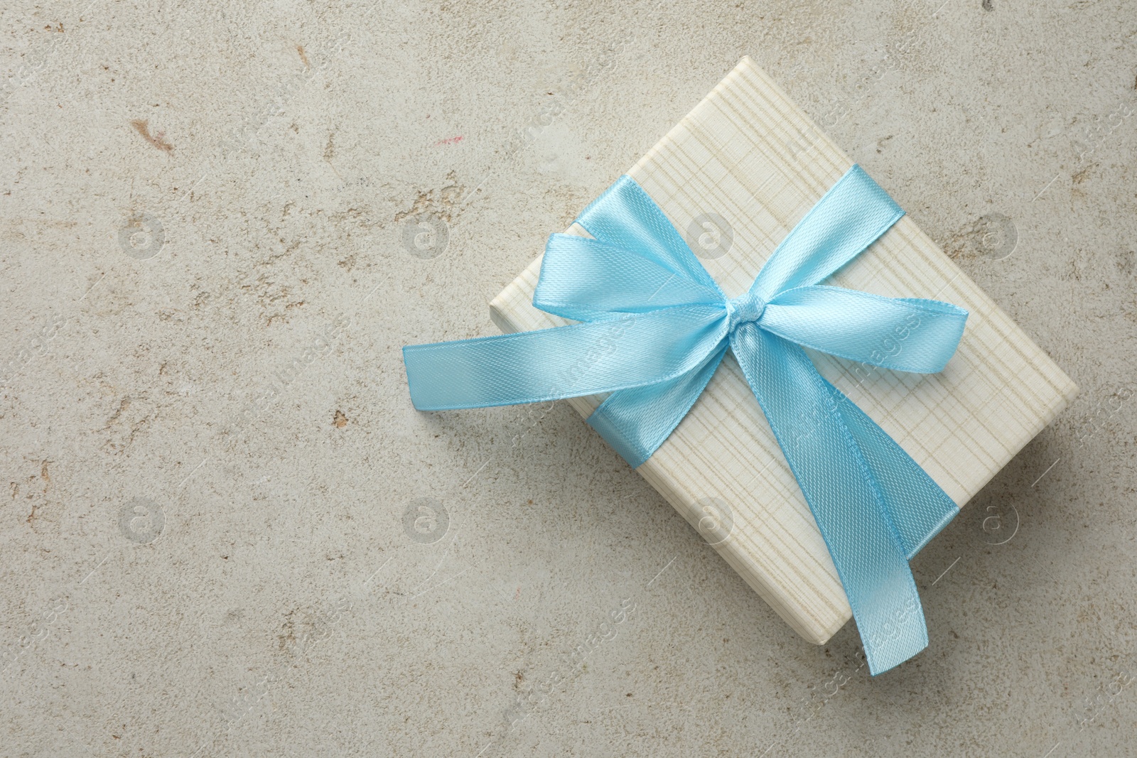 Photo of Beautiful gift box with bow on light grey table, top view. Space for text