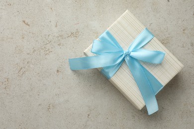 Photo of Beautiful gift box with bow on light grey table, top view. Space for text