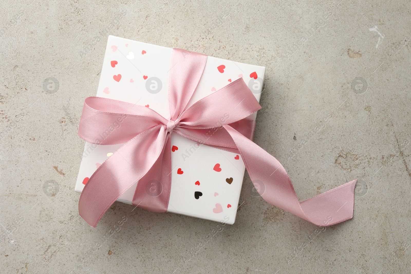 Photo of Beautiful gift box with pink ribbon on light grey table, top view