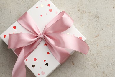 Photo of Beautiful gift box with pink ribbon on light grey table, top view. Space for text