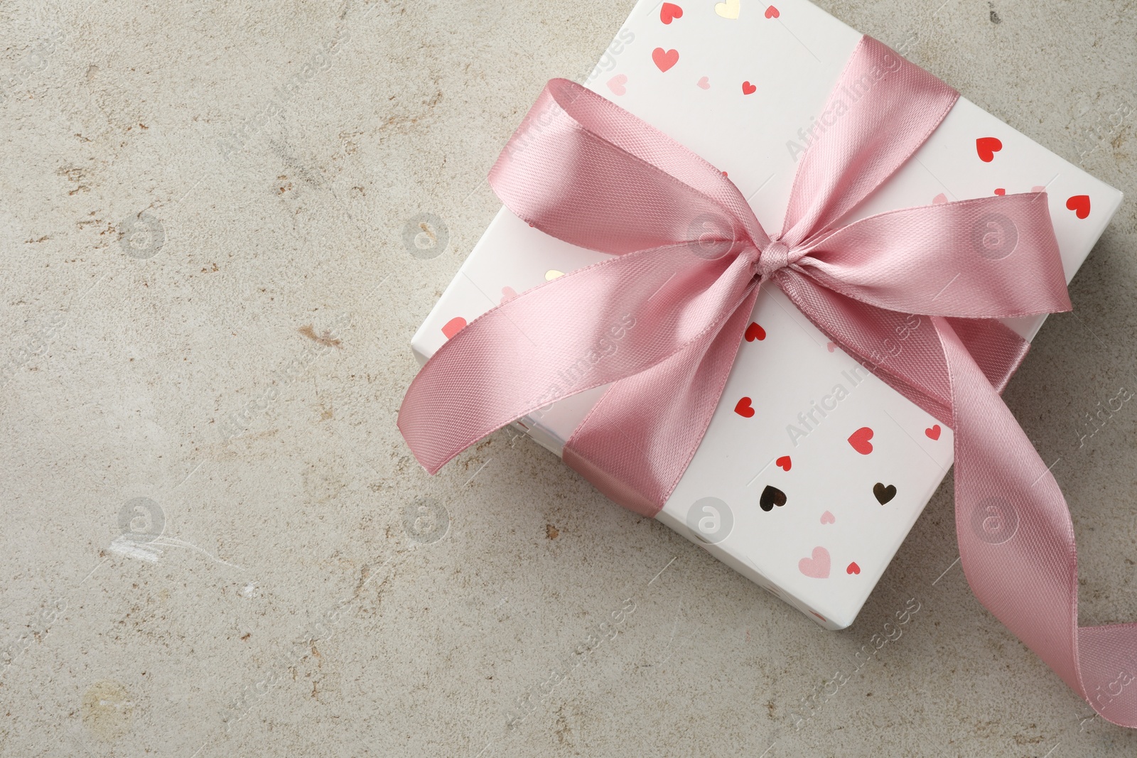 Photo of Beautiful gift box with pink ribbon on light grey table, top view. Space for text