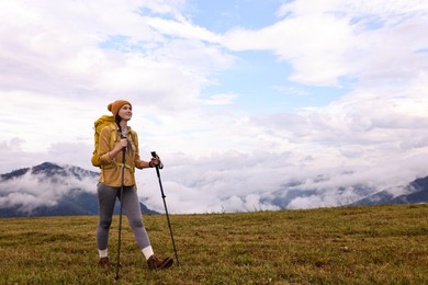 Photo of Young hiker with trekking poles and backpack in mountains outdoors, space for text