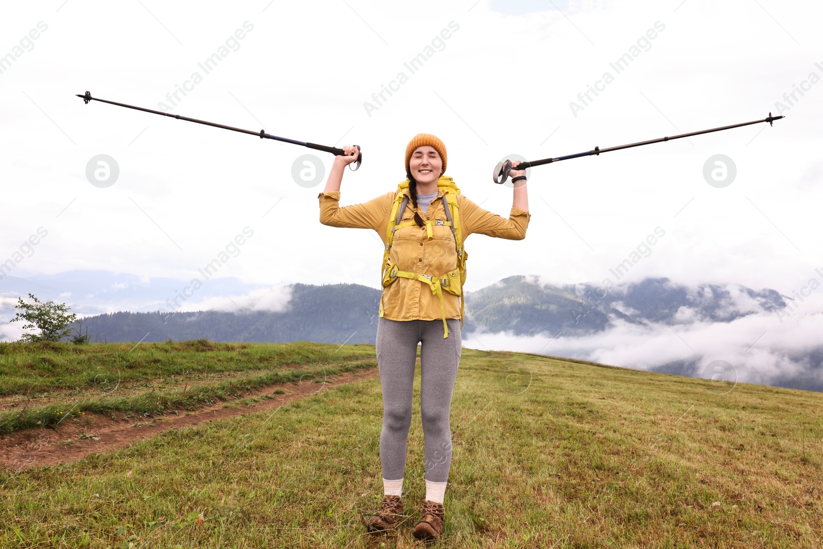 Photo of Young hiker with trekking poles and backpack in mountains outdoors