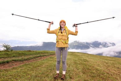 Photo of Young hiker with trekking poles and backpack in mountains outdoors