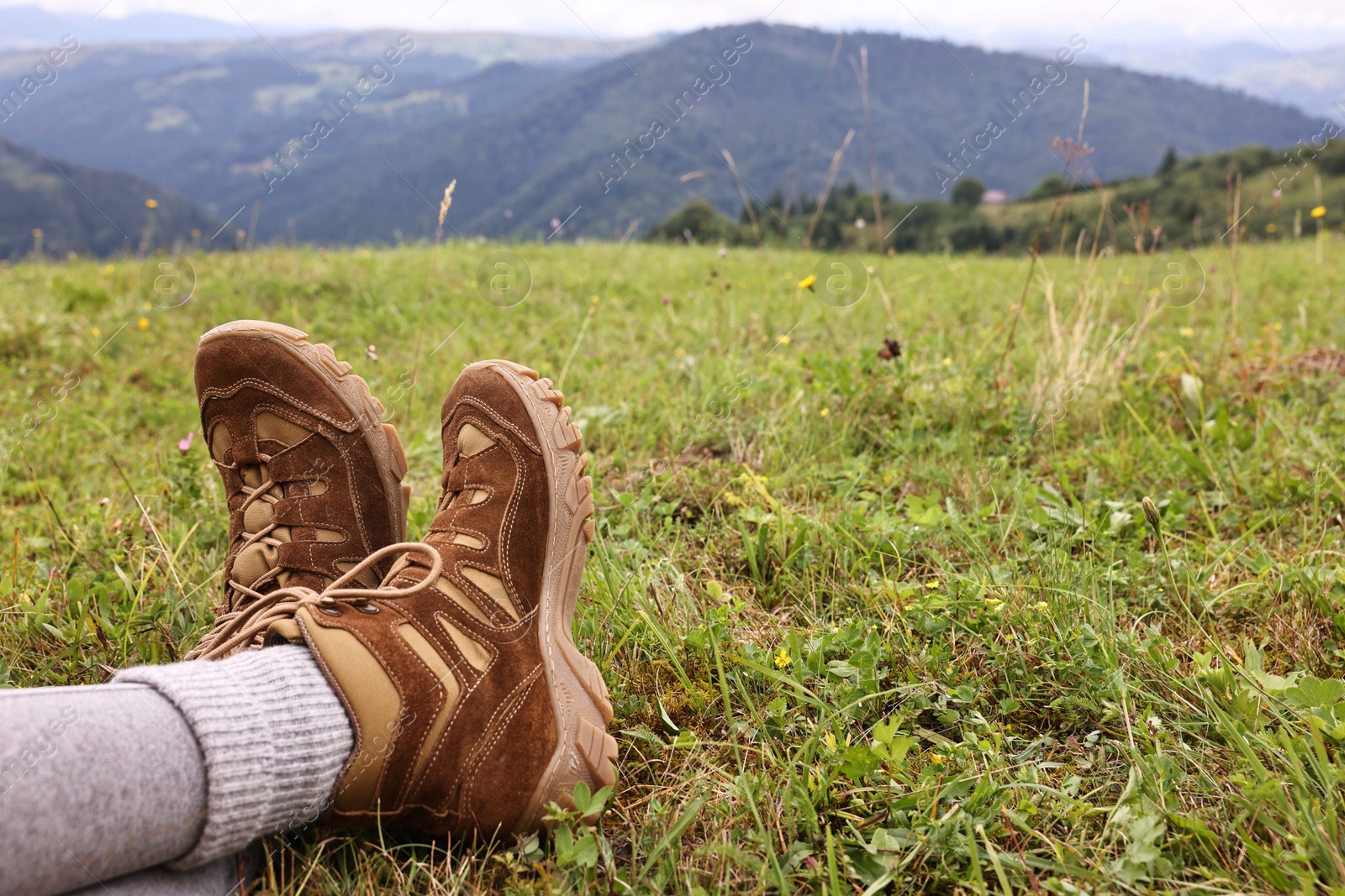 Photo of Young hiker wearing trekking shoes in mountains, closeup. Space for text