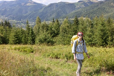 Happy young hiker with backpack in mountains