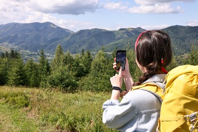 Young hiker taking picture with smartphone in forest