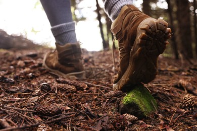 Photo of Hiker in trekking shoes walking in forest, closeup