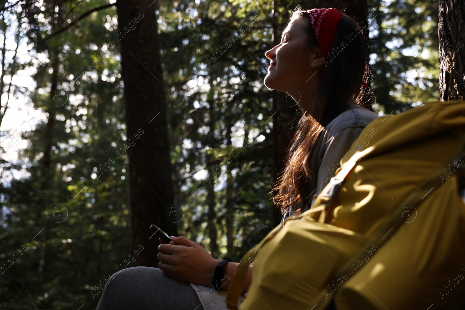 Photo of Young hiker with smartphone in forest, low angle view