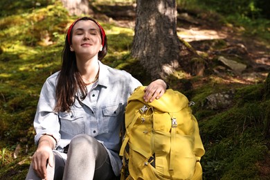 Young hiker with backpack resting in forest