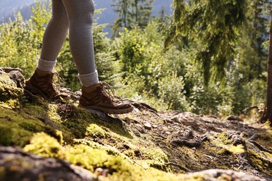 Photo of Young hiker wearing trekking shoes outdoors, closeup