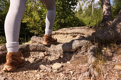 Photo of Young hiker in trekking shoes walking outdoors, closeup