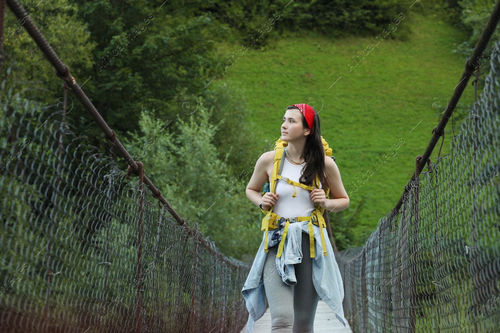 Photo of Young hiker walking on bridge in mountains