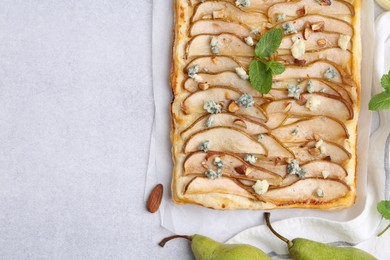 Photo of Delicious puff pastry tart with pears, almond, mint and blue cheese on light table, flat lay. Space for text