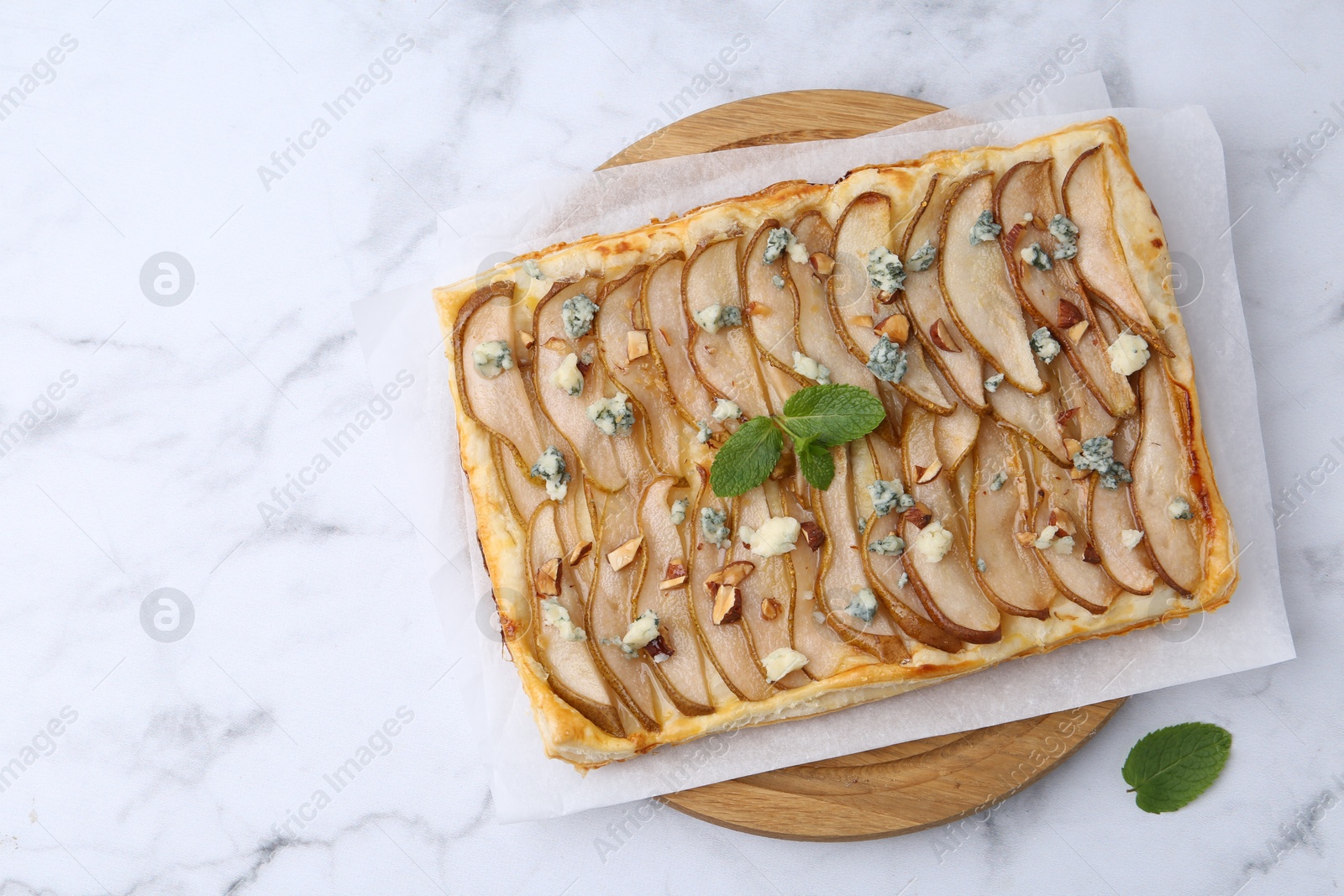 Photo of Delicious puff pastry tart with pears, almond, mint and blue cheese on white marble table, top view. Space for text